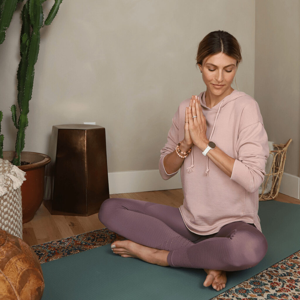 Vrouw op yogamat met Garmin dames smartwatch Lily om pols.